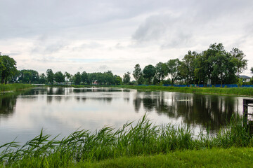 Fototapeta premium A small lake in a city park on a cloudy summer day in the city of Vetka, Gomel region
