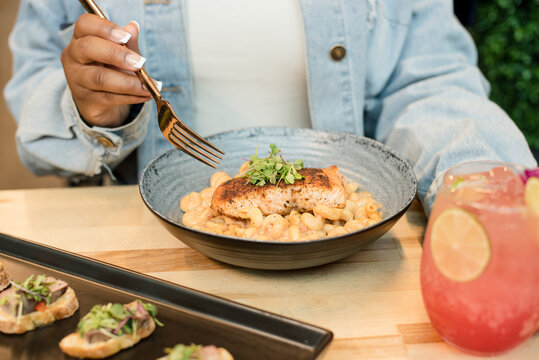 Woman at a table eating salmon and back and cheese