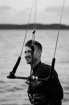Middle aged man kite surfing, holding a bar in his hands.