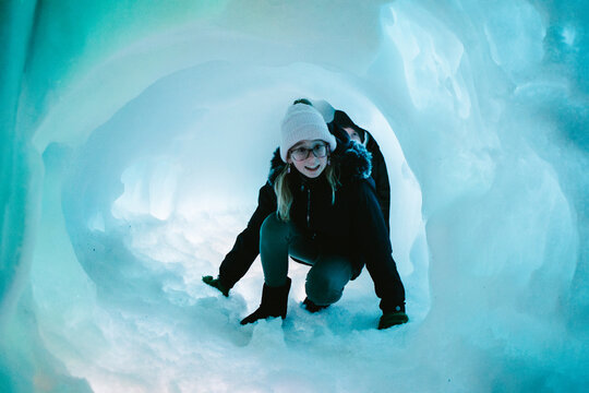 The girls crawls through snow tunnel at ice cave
