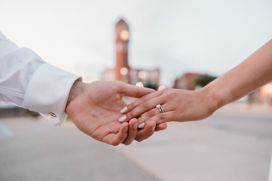 Bride and groom holding hands, blurred clock tower in the background