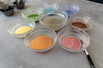 Collection of vibrant paint colors in glass bowls arranged on a table for an art project