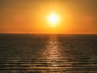 Golden sunset over the sea with a distant ship on the horizon