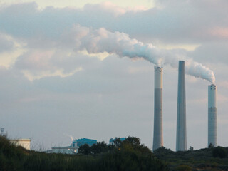 Industrial smokestacks releasing pollution into a cloudy sky