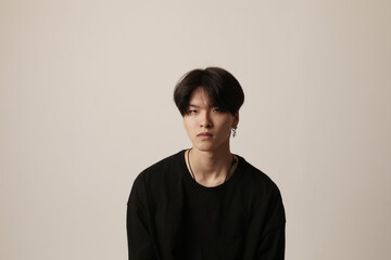 Portrait of unhappy young Asian man wearing casual t-shirt posing indoor over white background.