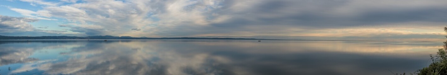 ampissima composizione panoramica con vista sul golfo di Trieste, nel mare Adriatico, al tramonto, in autunno, guardando verso la costiera di Trieste, sotto un cielo nuvoloso che si riflette nel mare