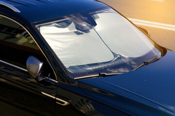 Parked car with windshield sunshade. Reflective car windshield sun shade made of aluminium foil,...