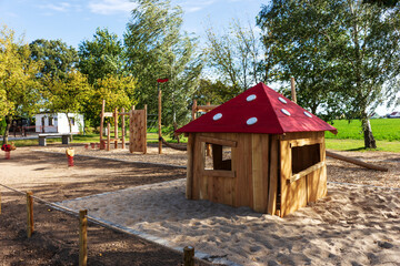 New wooden playhouse in outdoor public playground. Public children's play area