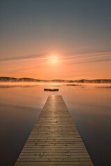 Obraz premium Wooden jetty in the morning at sunrise in the fog, on a Swedish lake. Scandinavian