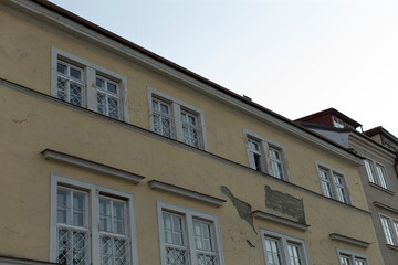 There exists a considerably large structure featuring a clock affixed to its side, standing prominently in the vicinity of other buildings
