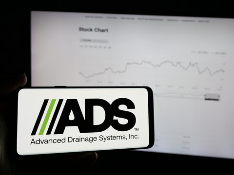 Stuttgart, Germany - 10-08-2024: Person holding mobile phone with logo of US company Advanced Drainage Systems Inc. (ADS) on screen in front of web page. Focus on phone display.