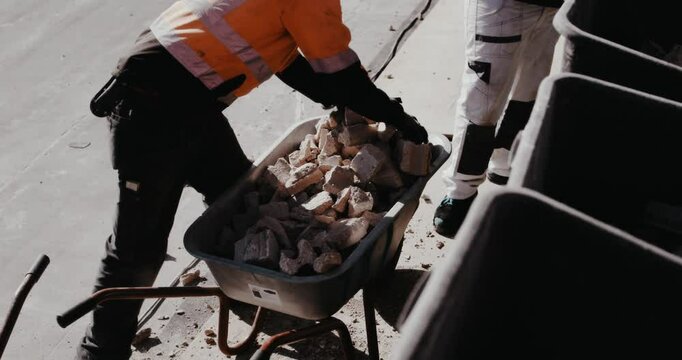 Bauarbeiter kippen Schutt in Schubkarre