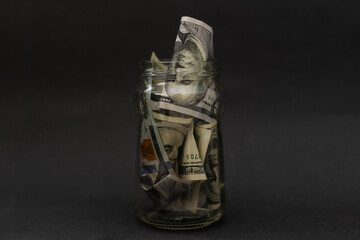 Many 100 US dollars bank notes in a glass jar isolated