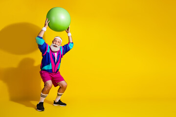 Full length photo of cheerful positive mature guy dressed retro sport jacket squatting fit ball...