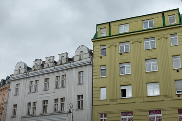 In the city, a bright yellow building that features a vibrant green roof stands proudly next to a pristine white building nearby
