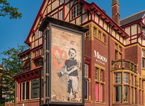 Amsterdam, Netherlands - June 30, 2019: View of stencil graffiti with the boy. Street Art by Banksy. Moco museum, located in the Alsberg mansion on the Museum Square.