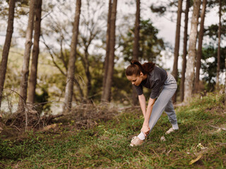 Young woman stretching in a serene forest, wearing comfortable sportswear and focusing on her fitness routine Nature and wellness concept