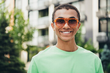 Photo of nice young man beaming smile wear t-shirt free time walk downtown street outdoors