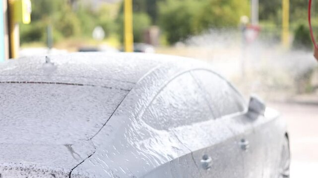 Cleaning car using active foam. Handsome man washing his luxury car on self car-washing