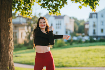 A young woman stretches with a joyful expression, surrounded by lush greenery and a sunlit backdrop...