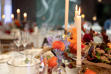 Aesthetic stylish autumn table setting background, arranged flowers and candles under natural light.