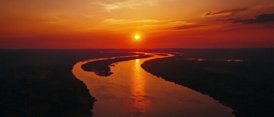 Naklejka premium A winding river cuts through a forest, reflecting the fiery suns