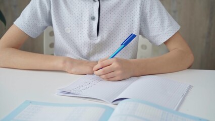 A close-up of a schoolboy's hands with a pen, focused on studying and writing notes