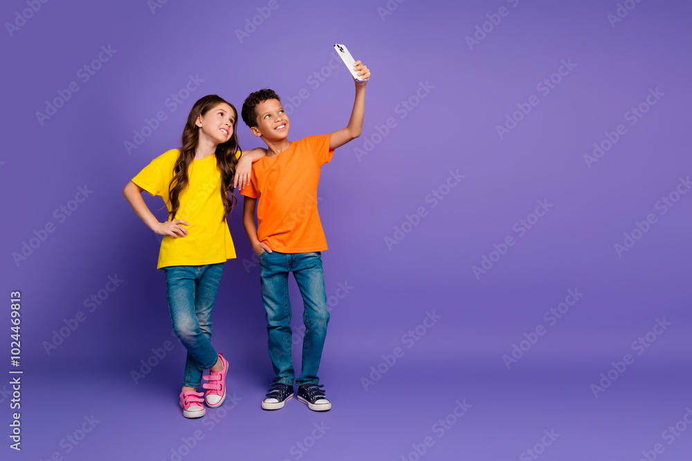 Poster Full length photo of lovely two little kids take selfie photo dressed stylish orange yellow garment isolated on purple color background