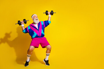 Full body photo banner of funny senior sportsman lifting weights dressed stylish retro sport costume isolated on yellow color background