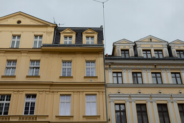 A yellow building that features a distinctive black roof is situated right next to another yellow building that also shares similar architectural elements