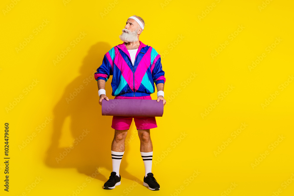 Wall mural Full length photo banner of sportive cheerful old man hold mat look empty space dressed retro sportswear isolated on yellow background