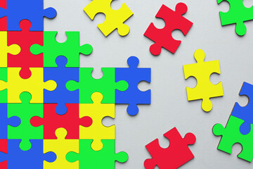 Obraz premium Many colorful puzzle pieces on light grey background, top view. Symbol of autism