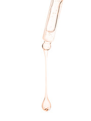 Cosmetic oil dripping from pipette on white background, closeup