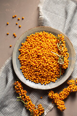 A plate with orange berries on a table with a gray napkin