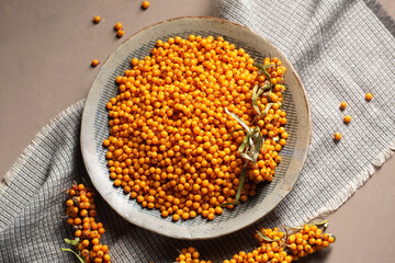 A plate with orange berries on a table with a napkin