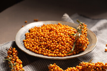 A plate with orange berries stands on a table with a napkin, close-up