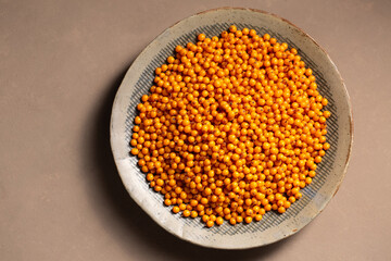 A plate with orange berries on a table with a gray napkin, top view