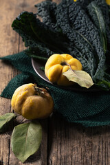 A plate leafy of kale and yellow quince on a wooden table