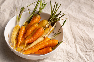A colorful organic carrots on a light tablecloth
