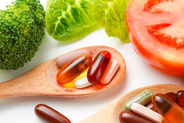 Pills and capsules in wooden spoon with fresh vegetables, Multivitamins and supplement