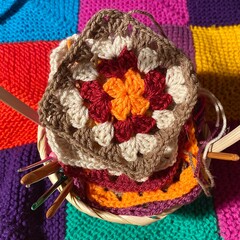 Crochet granny square, clews and hook on knitted blanket background photo	
