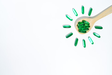 Green pills herbal medicine, Green oil pills Vitamin E, Softgels green in a wooden spoon