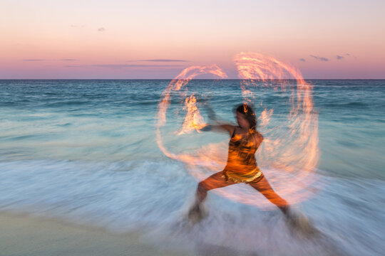 Traditional mexican fire dancer at sunset on the beach,  Mexico