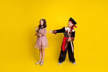 Full size photo of two little kids theater play halloween pirate princess costume isolated on yellow color background