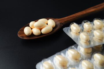 white softgels in wooden spoon, capsules with vitamin E, Cod liver oil, DHA, Fish oil omega 3