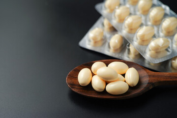 white softgels in wooden spoon, capsules with vitamin E, Cod liver oil, DHA, Fish oil omega 3