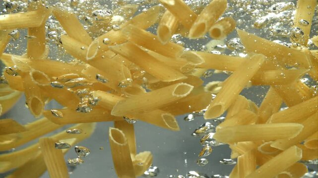 Penne pasta falls into boiling water. Filmed on a high-speed camera at 1000 fps. High quality FullHD footage
