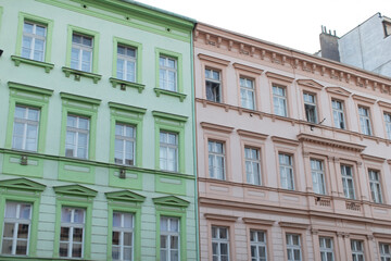 A bright green building and a vibrant pink building are positioned right next to each other in the bustling city area