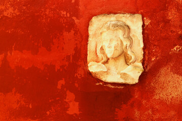 Wall with red plaster and generic female figure in high relief in white stucco