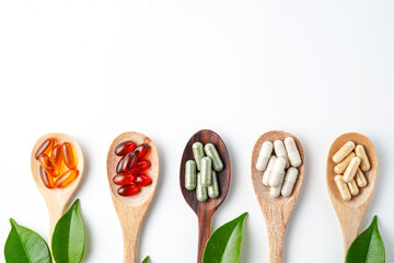 Wooden spoon with assorted herbal vegan vitamin capsules for healthy lifestyle with fresh leaves